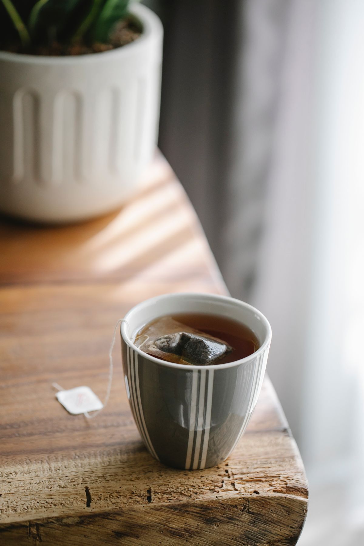 A glazed ceramic mug holding tea on a wooden table