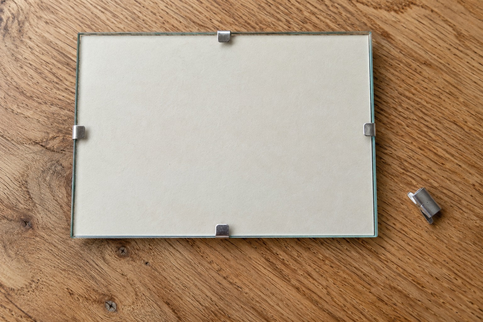Illustrative AI image: Frameless glass picture holder secured with small metal clips