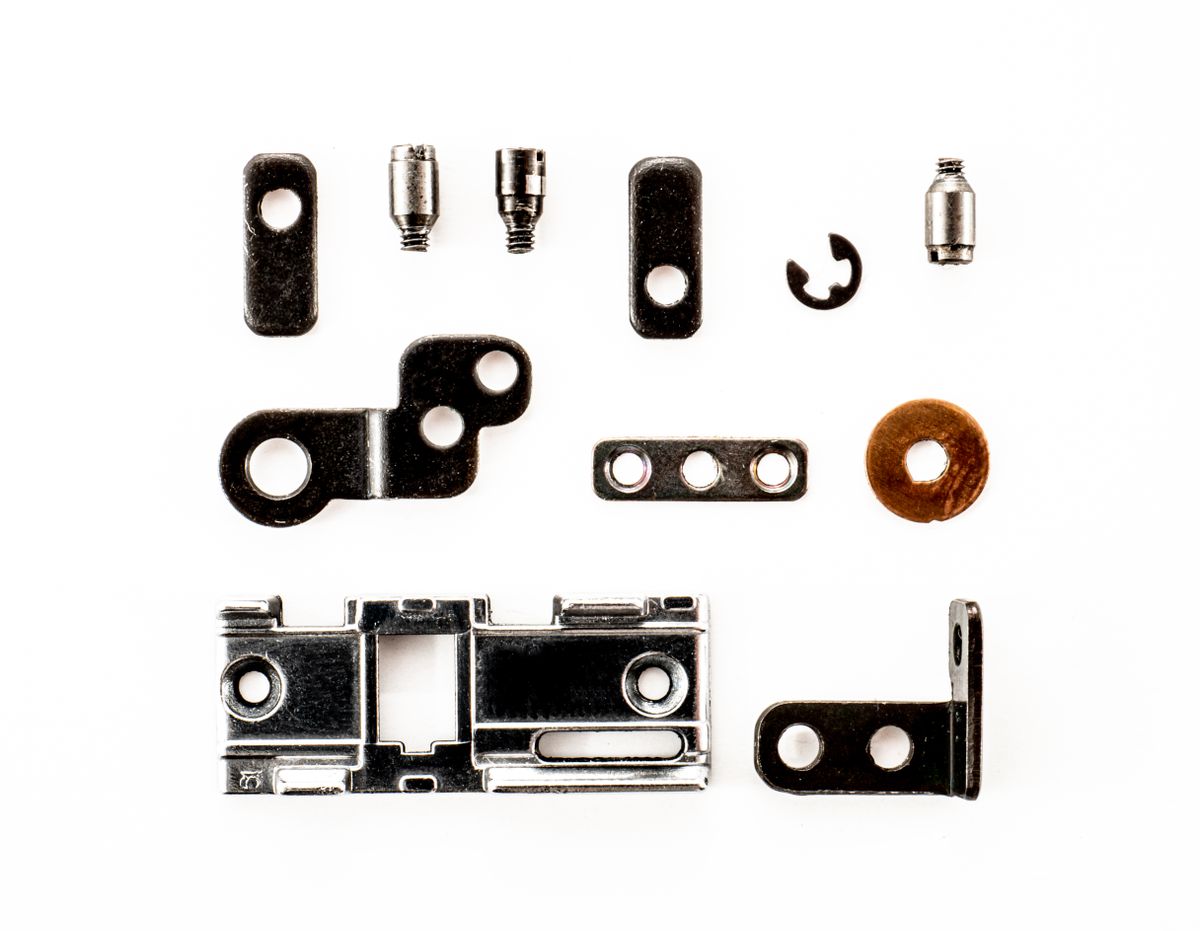 Small metal furniture connectors arranged on a white surface