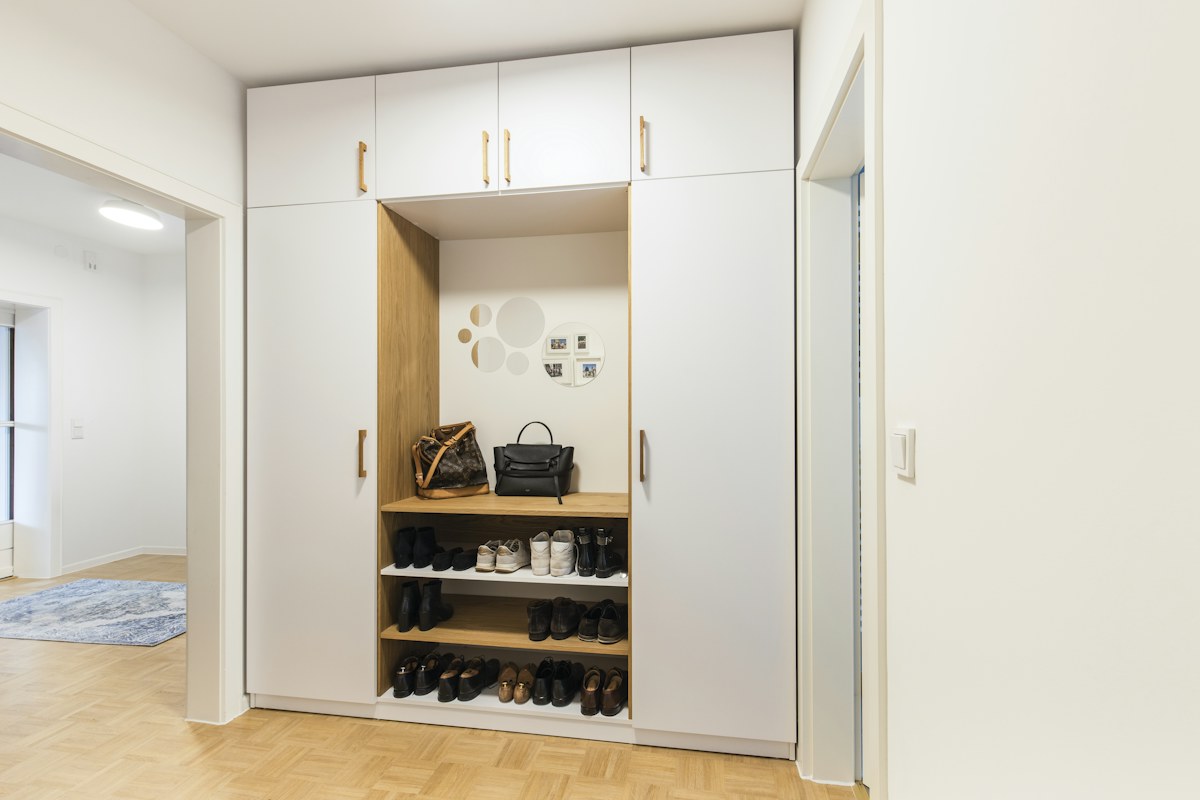 Shoes arranged on open shelves in a fitted hallway cupboard