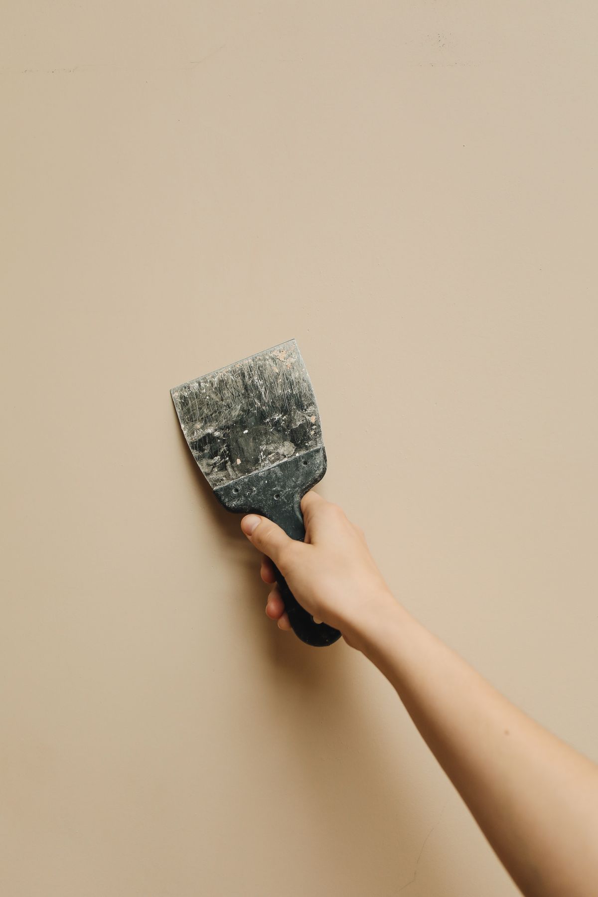 A filling knife being held against an interior wall