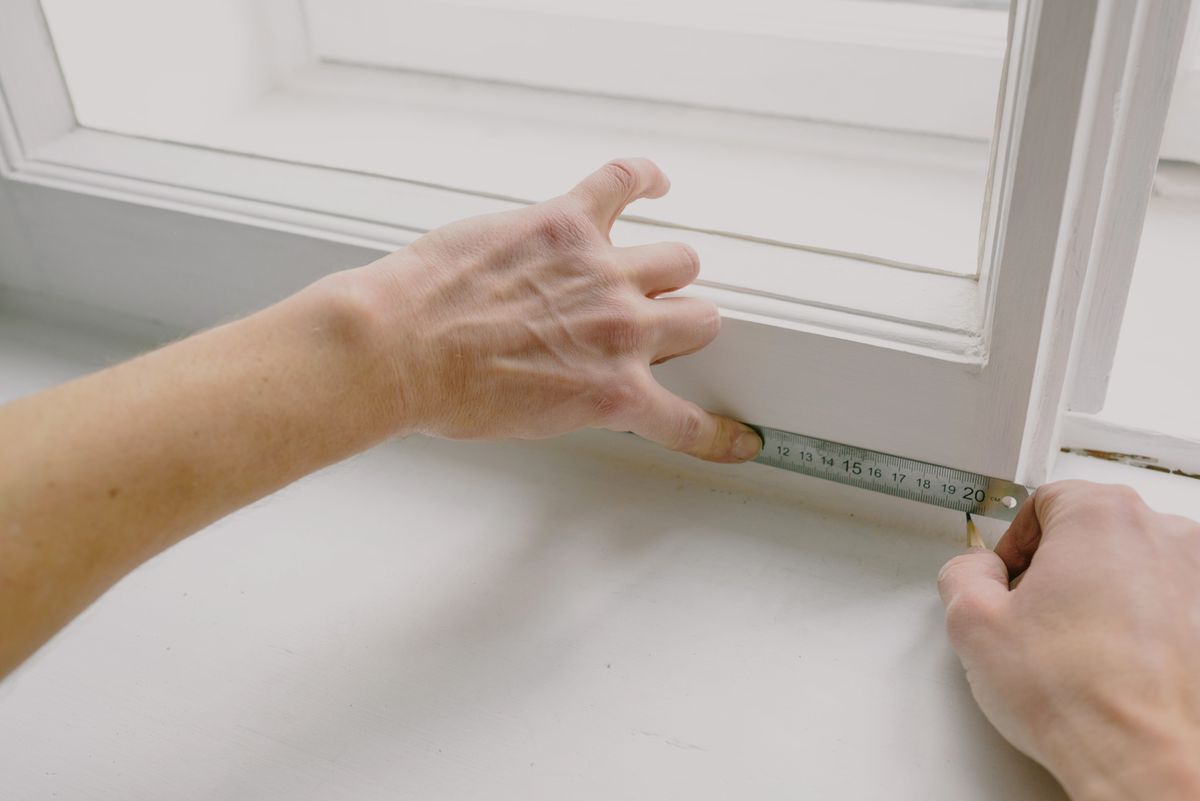 Window frame being measured with a tape