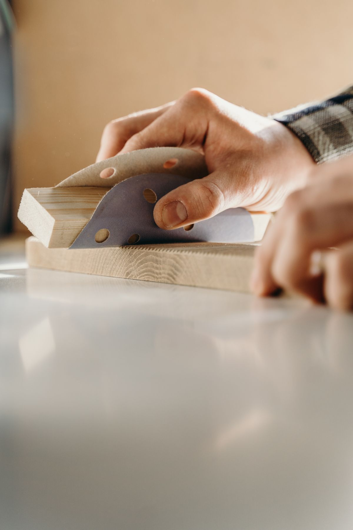 Hands sanding a bare timber block